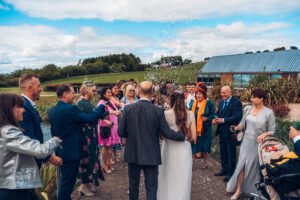 Bride and groom walking out after the ceremony and guests are throwing in rice.