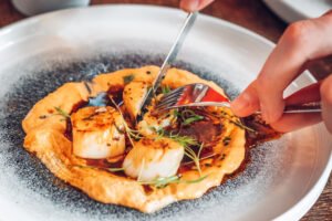 Hand dived scallops being carved by a person.