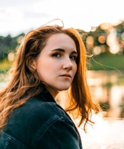 Red haired girl during sunset next to the pond.