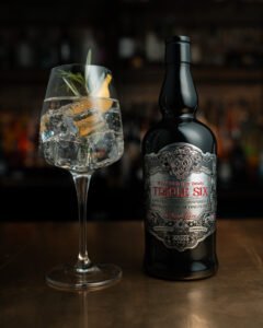 Triple six gin bottle next to a cocktail