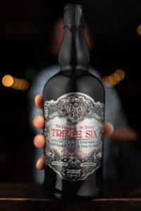 A man holding a triple six gin bottle in his hands