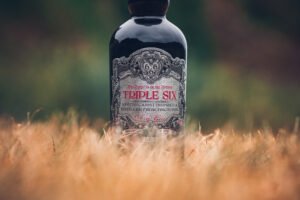 Half of the bottle of gin peaking out from behind the grass.